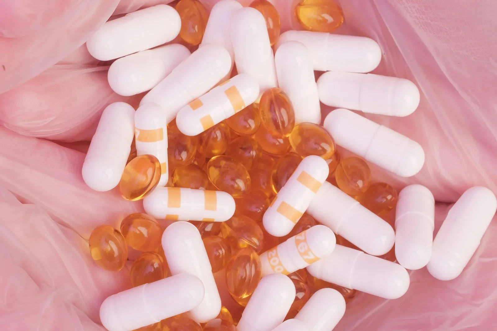 Cross-links and further reading: Top view unrecognizable person in sterile gloves showing heap of assorted drugs and vitamin capsules