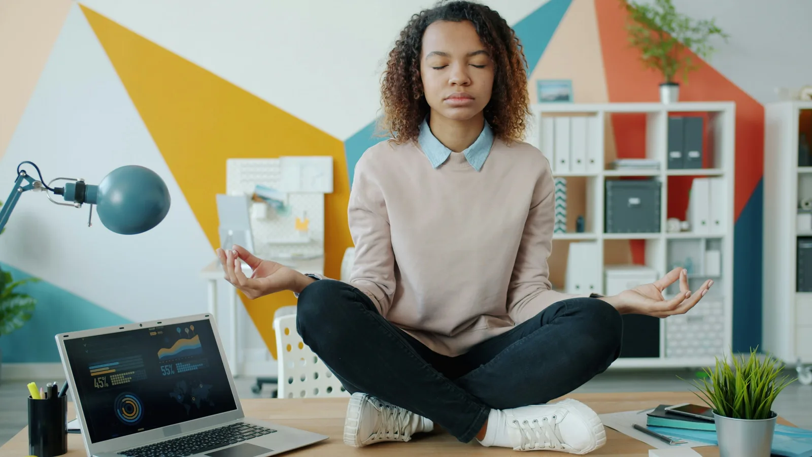 Stacking with other interventions: Woman meditating at a desk with laptop.
