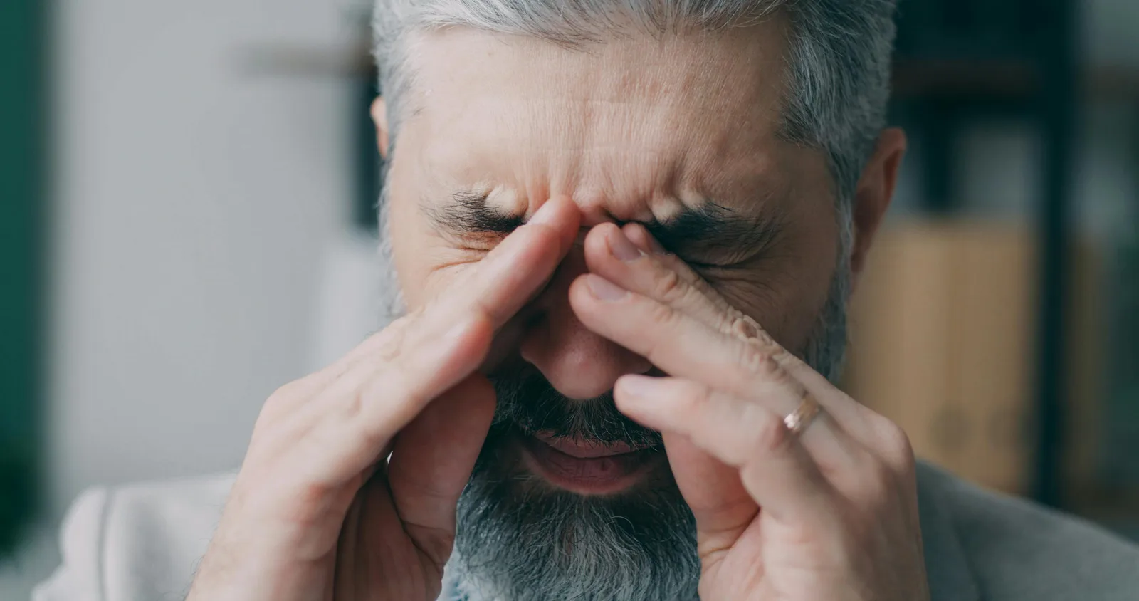 What chronic stress does cellularly: Close-up of a senior man rubbing his eyes experiencing stress indoors.