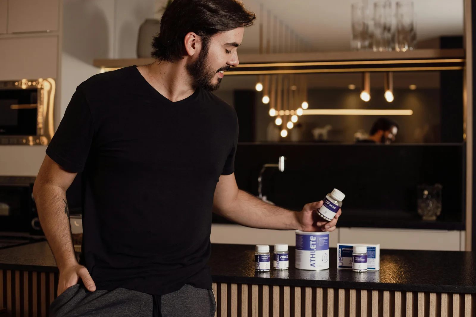 The counter-view: A man examines supplement bottles on a modern kitchen counter, reflecting a healthy lifestyle.
