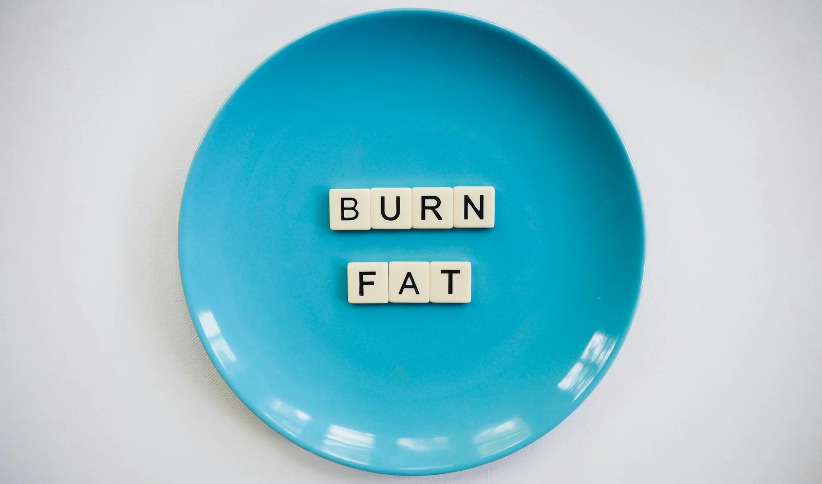 What is the right architecture for sustainable fat loss?: A conceptual image featuring the words 'Burn Fat' on a blue plate, symbolizing weight loss.