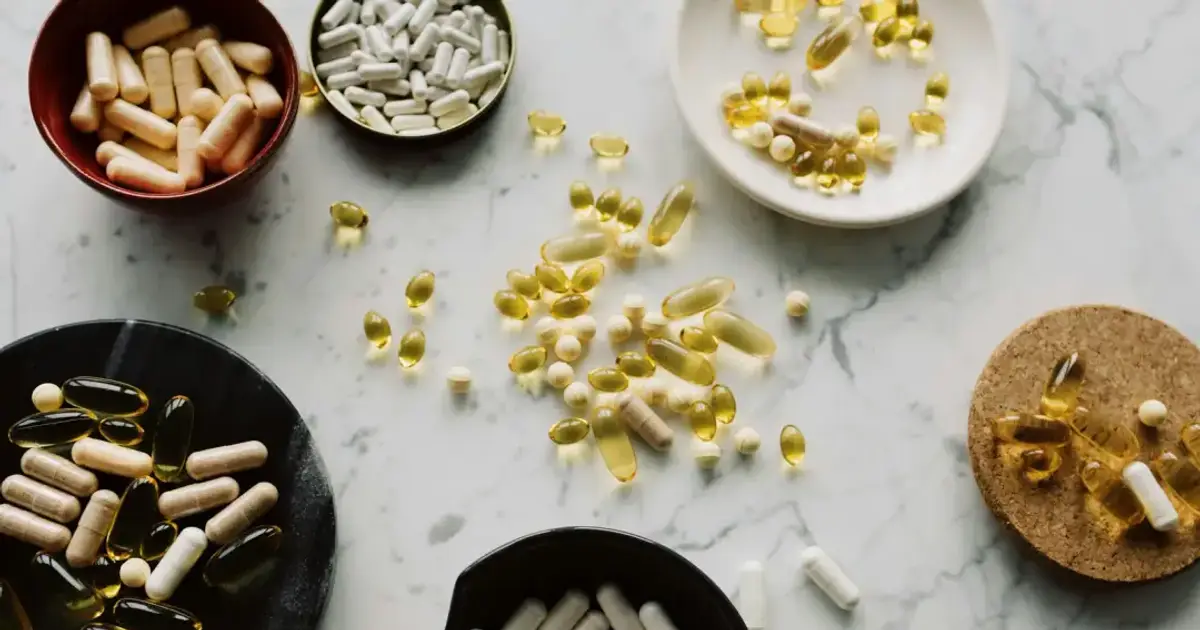 From above of various types of medication pills and yellow capsules of omega placed on different plates and stands on table