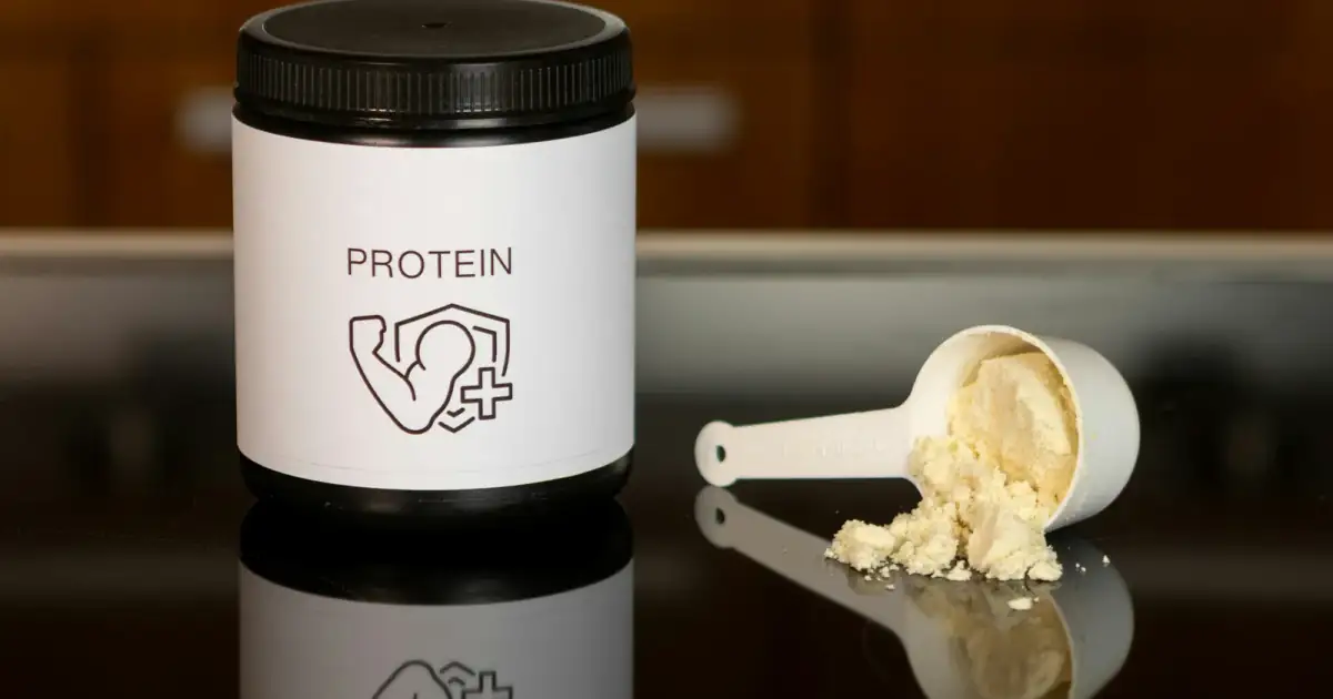 a container of protein powder next to a spoon