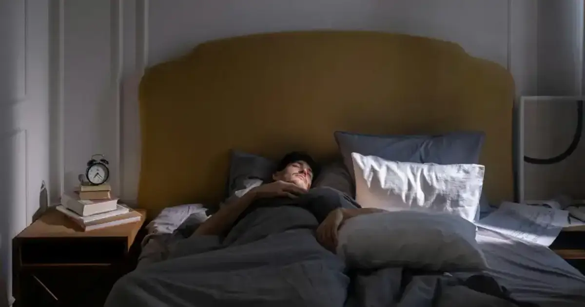 A man sleeping in a cozy bed with soft morning sunlight filtering in.