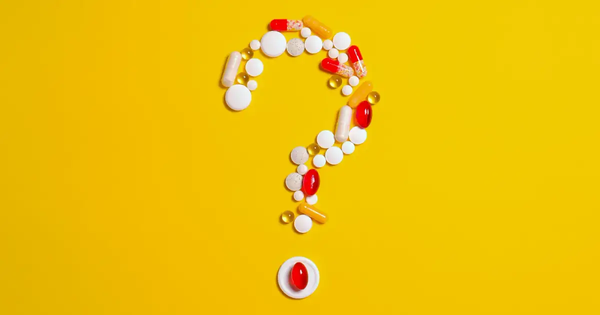 Assorted pills and capsules arranged in a question mark on a bright yellow background symbolizing medication inquiries.