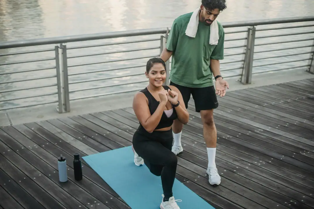 When HRV-guided training works and when it doesn't: Man and woman exercising by a riverside, focused on lunges and fitness training.