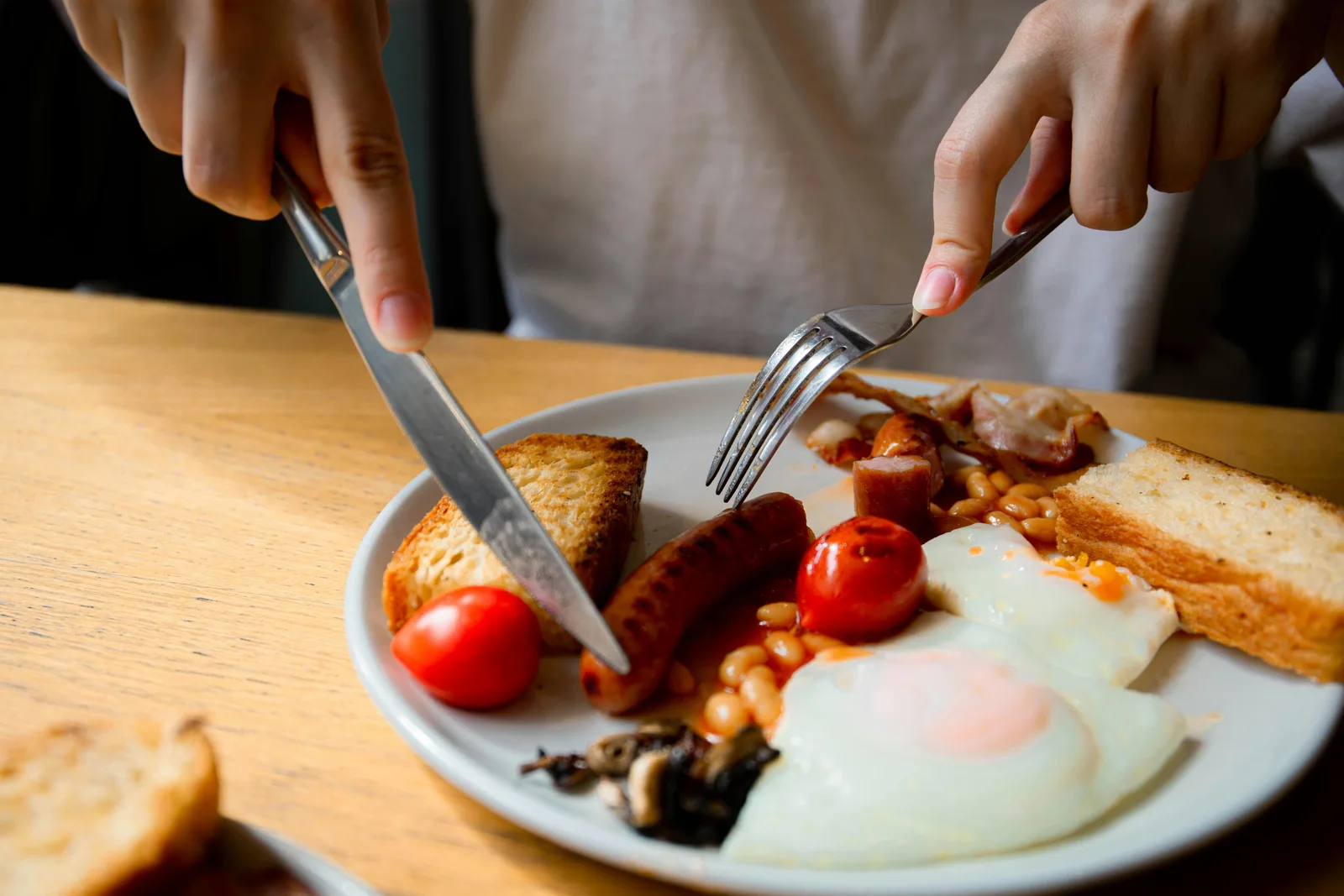 The skip breakfast debate: Close-up of a traditional English breakfast with eggs, bacon, and sausage on a plate.