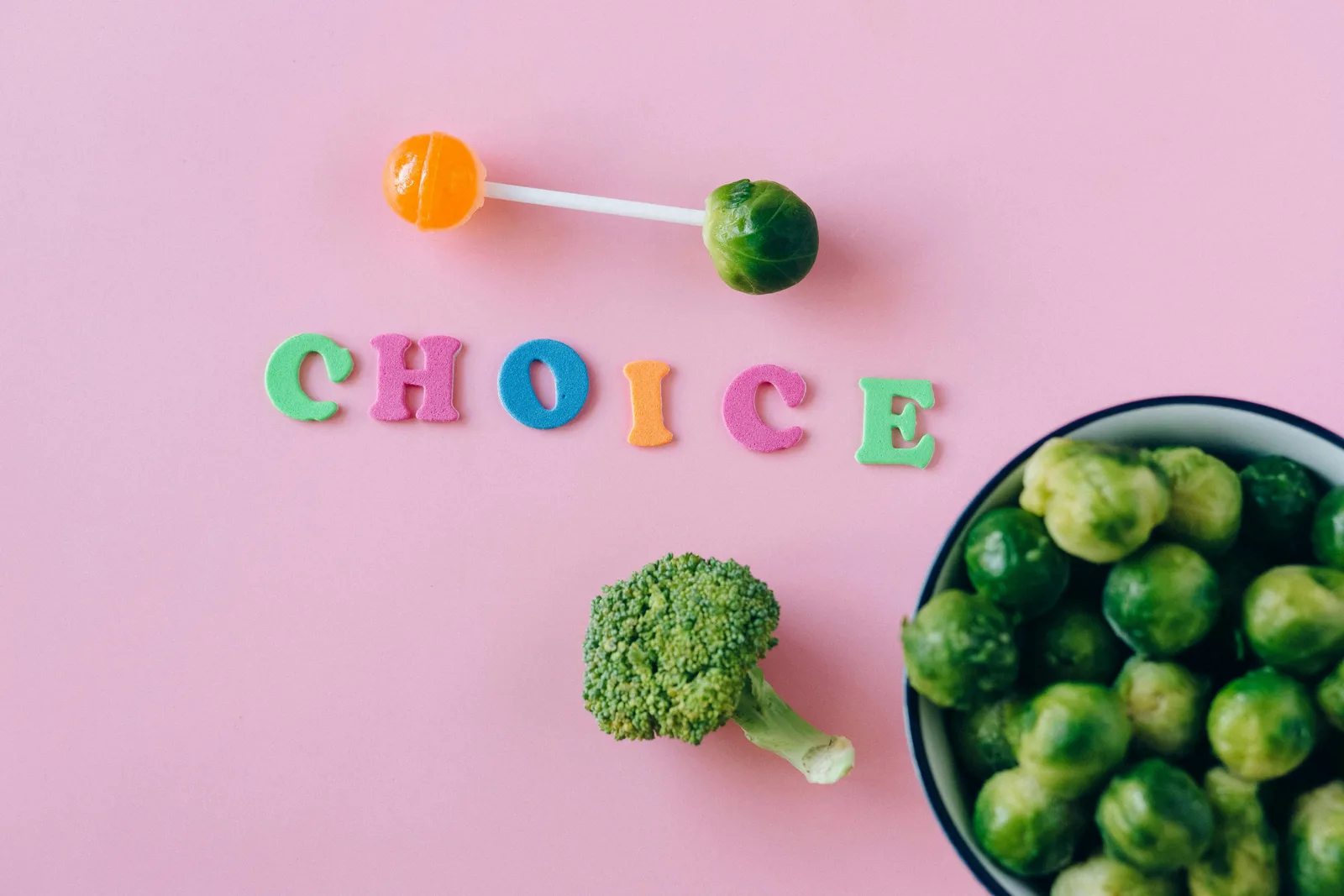 Stacking and timing: Colorful depiction of healthy and sweet food choices on pink backdrop.