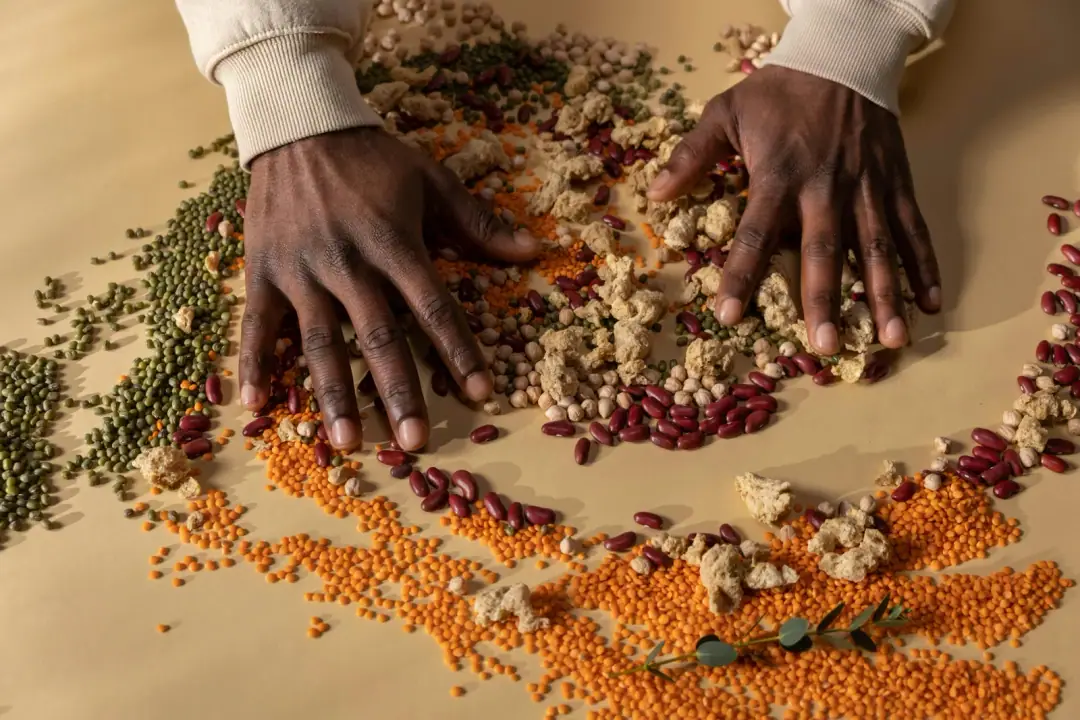 The age-adjusted target table: Top view of hands mixing colorful grains and vegan ingredients on a table.