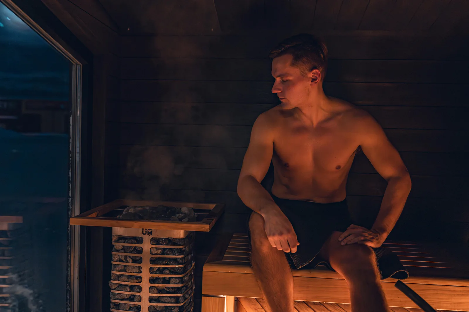 The Finnish cohort data: A shirtless man relaxes in a modern Nordic sauna, experiencing the warmth and benefits of steam.