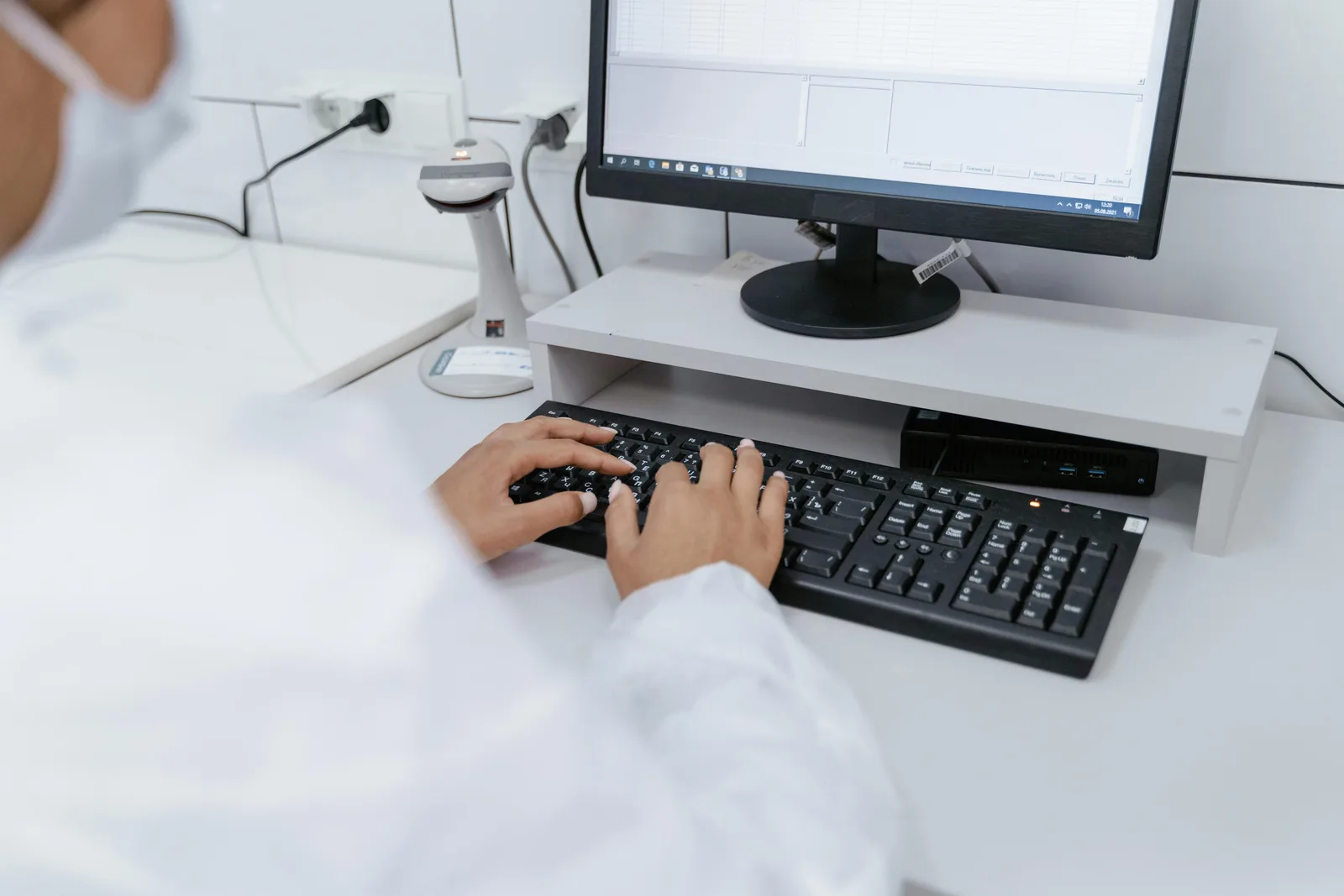 The evidence gap: mouse data vs human trials: Scientist in white coat using a computer in a laboratory setting, focusing on data analysis.