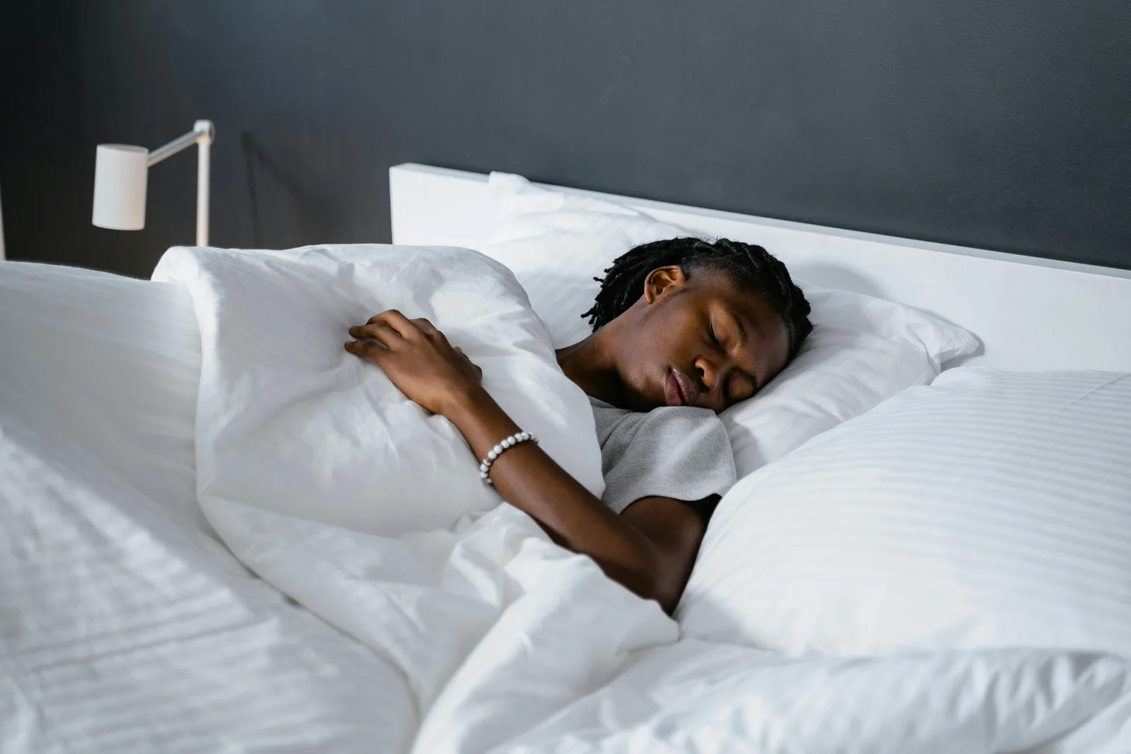 Tier 2: moderate effect, still easy: A man sleeping peacefully under a white blanket in a cozy bedroom.