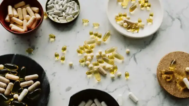 From above of various types of medication pills and yellow capsules of omega placed on different plates and stands on table