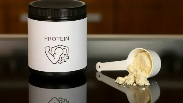 a container of protein powder next to a spoon
