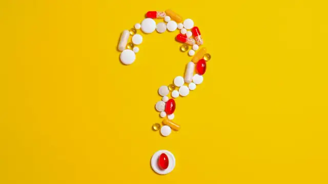 Assorted pills and capsules arranged in a question mark on a bright yellow background symbolizing medication inquiries.