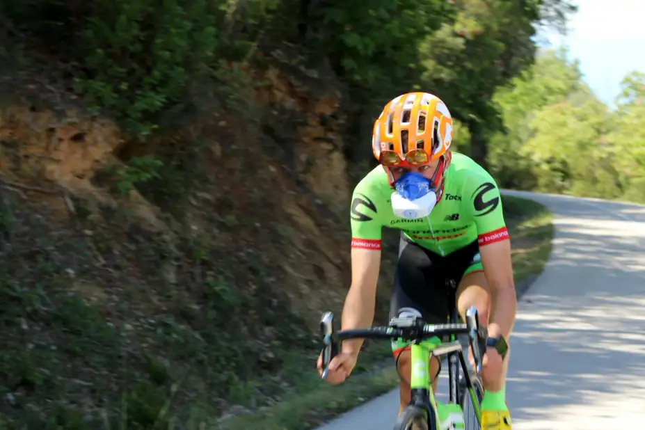 Why do Zone-2 and VO2 max predict mortality so strongly?: High-performance cyclist using VO2 mask on a winding road, showcasing speed and endurance training.