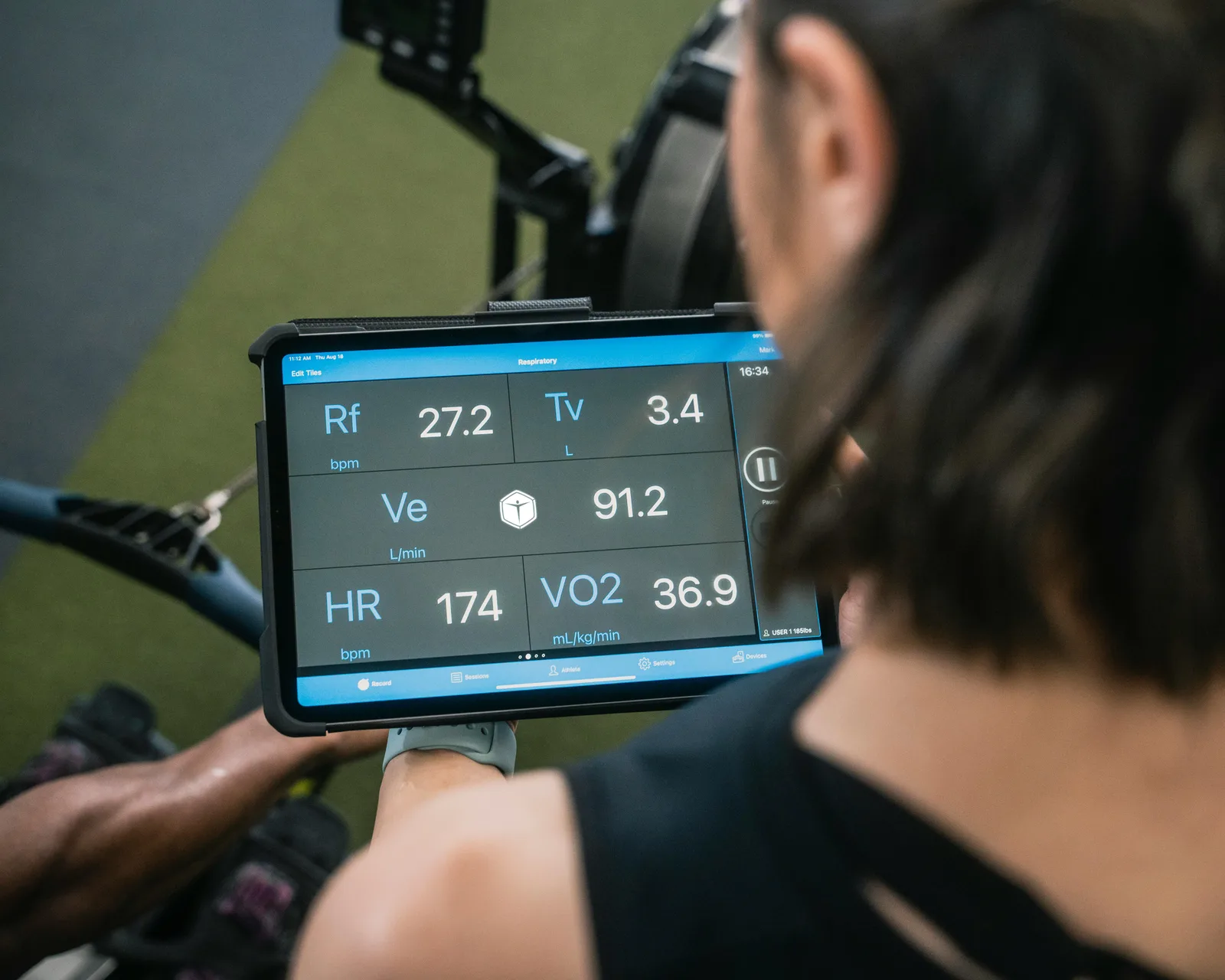 The counter-view: Adult man reviewing fitness metrics on a tablet during a workout session at the gym.